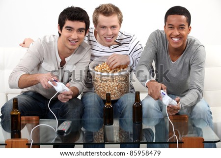 Three friends playing video games while drinking beer.