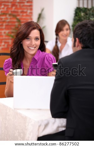 Couple sitting in a restaurant drinking expresso and looking at a laptop computer