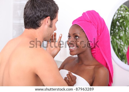 Man and woman messing around with moisturizer in the bathroom