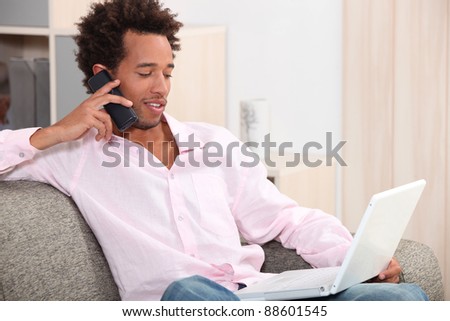 young man sitting on sofa with laptop making a call