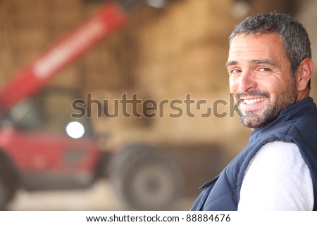 Farmer stood in front of bails of hay