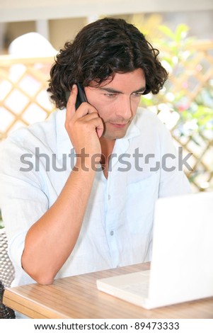 Man sat with laptop and telephone on terrace