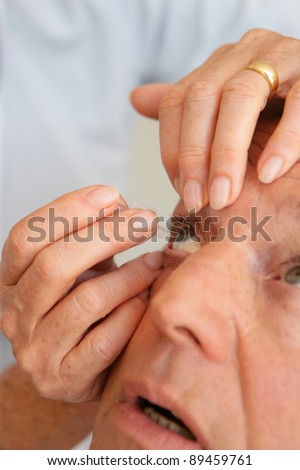 Woman helping man put in contact lenses