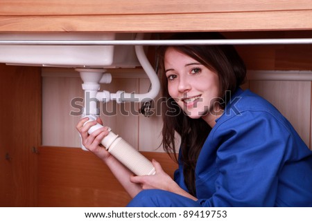 Young woman fitting the waste pipe on a kitchen sink