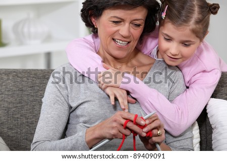 A mom showing how to knit to her daughter.
