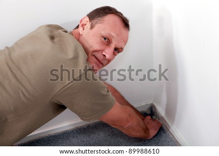 Man fitting carpet into a corner