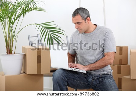 man amid removal boxes working on laptop