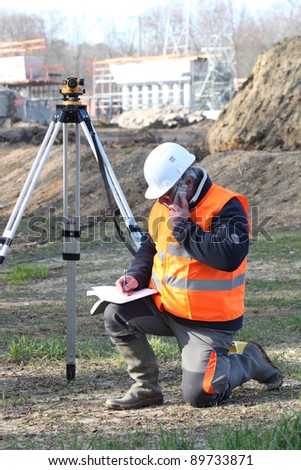 A land surveyor writing in his notebook while talking on the phone