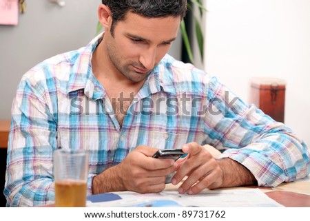 Man reading magazine and sending text message