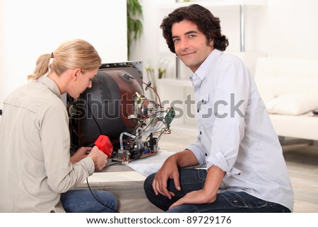 Couple repairing broken television