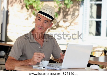 Senior with a laptop outside a cafe