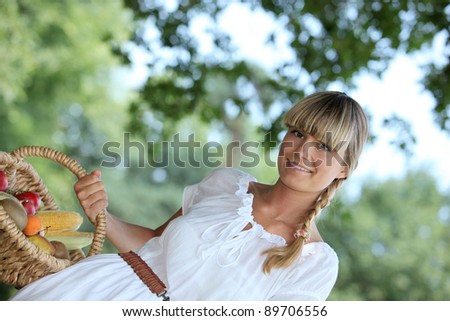Young blond woman carrying basket of fruit and vegetable
