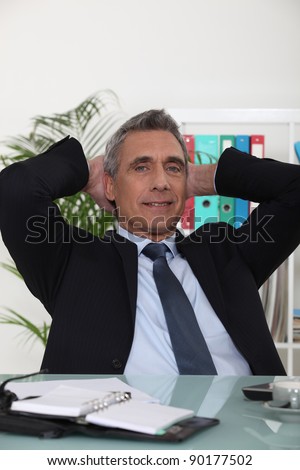 Portrait of an arrogant businessman with his hands behind his head