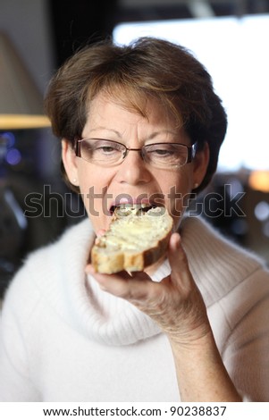 Woman eating a slice of buttered bread
