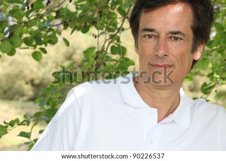 Man smiling in front of tree