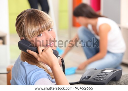 A teenage girl answering the phone at her place.