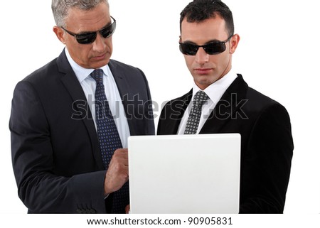 stock-photo-serious-men-in-smart-suits-with-sunglasses-holding-a-laptop-90905831.jpg