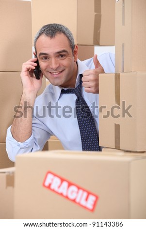 Happy man on phone behind stacks of boxes