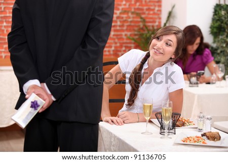 Man offering gift to woman in restaurant