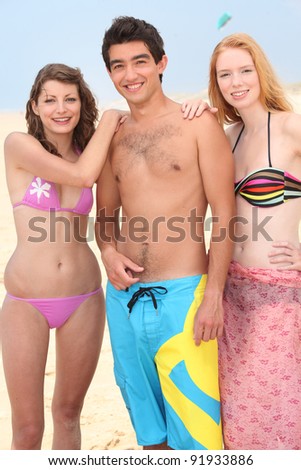 Three friends stand on a beach