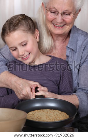 Girl and her granny cooking pancakes