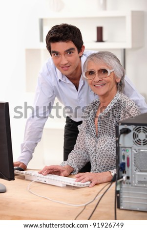 grandson explaining to his grandmother how to use a computer