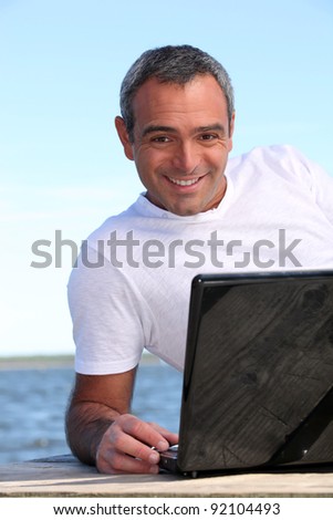 40 years old man doing computer behind the sea