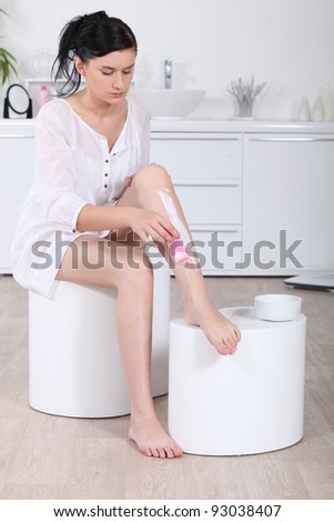 Woman using a hair removal cream on her legs