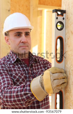 builder checking wall\'s verticality with a level tube