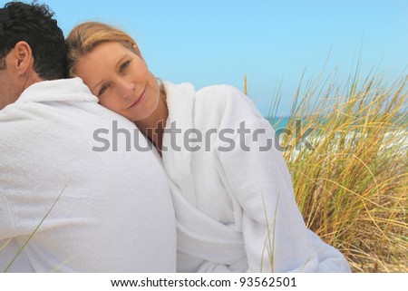 Couple sitting in the sand dunes in white toweling robes