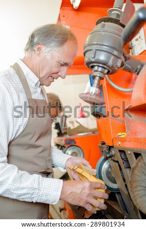 Cobbler using machinery on heel of shoe