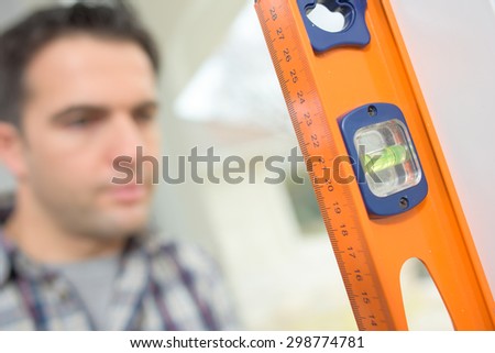 Builder using a spirit level to check a wall