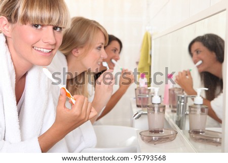 Females roommates brushing teeth