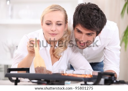 Couple cooking on a table top electric hotplate