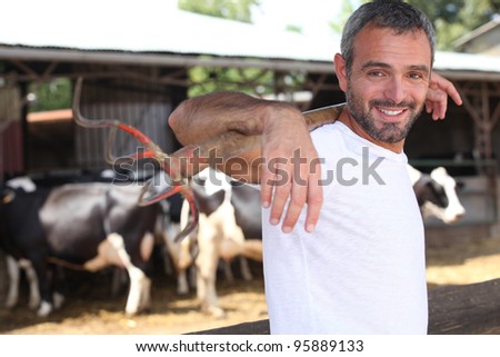 Farmer with pitchfork standing in front of cattle