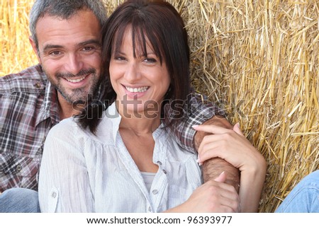 Farming couple sitting in the hay