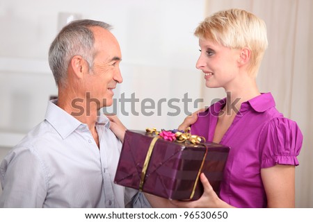 young woman giving a gift to an older man