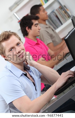 male students in class working on laptop