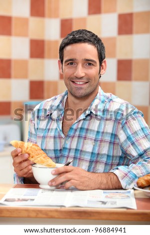 Man dunking a croissant into a cafe au lait at breakfast time