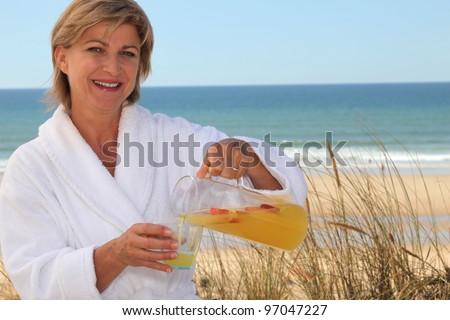 Woman pouring herself a glass of orange juice at the beach