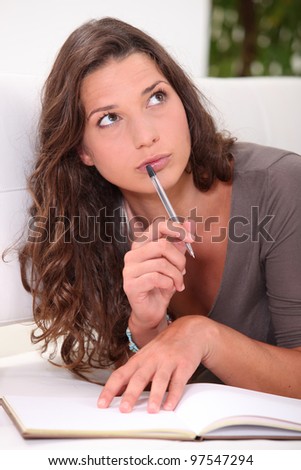 Young woman thinking about what to write in her book