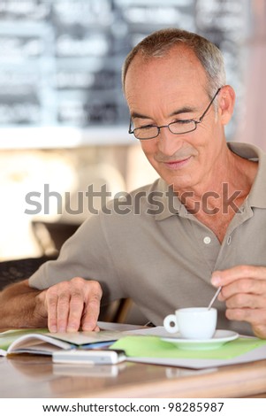 Old man drinking coffee and reading