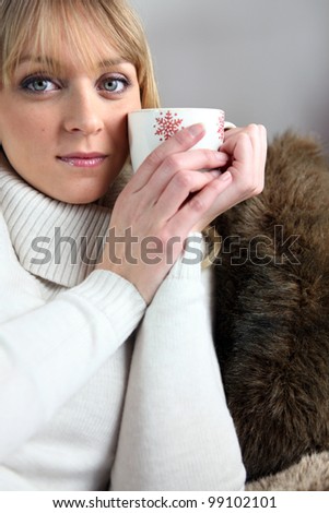 Blond woman sat on the sofa with a nice mug of coffee