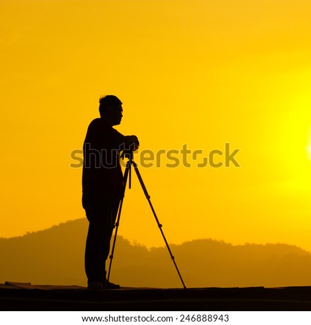 Man in silhouette holding a tripod & think of the future