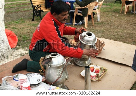 SRINAGAR, INDIA - APR 5, 2014: Indian merchant is pouring hot saffron tea while selling to customers at Srinagar, Jammu and Kashmir, India on Apr 5, 2014.