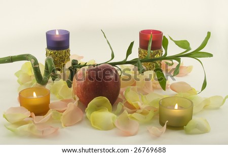 Bamboo and big red fresh apple with aromatic rose leave in rays of color candles