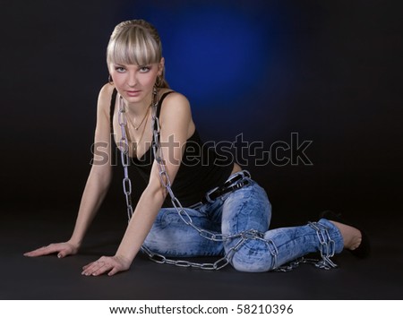 Sexy blonde in chains over black background