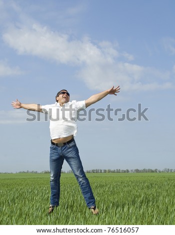 young man jumping a green field of grass
