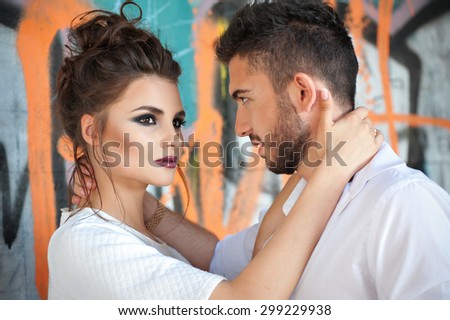 Brunette woman with aggressive makeup hugging man. Sexual young couple against graffity wall. Valentines Day