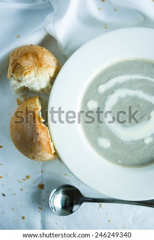 Mushroom cream Soup with bread  in white bowl and soup spoon on white fabric